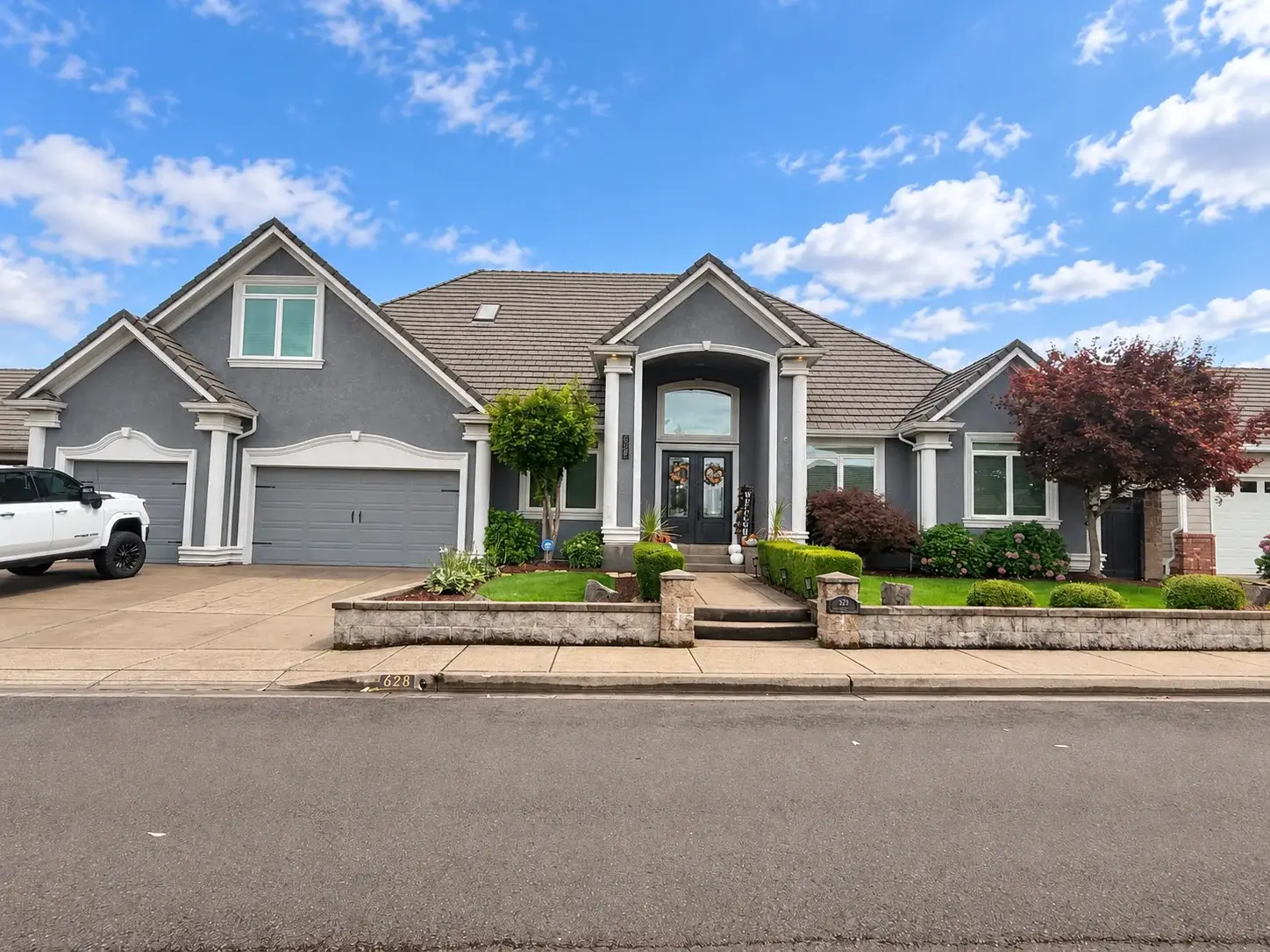 Gray stucco home with a columned entry, arched transom, and tile roof
