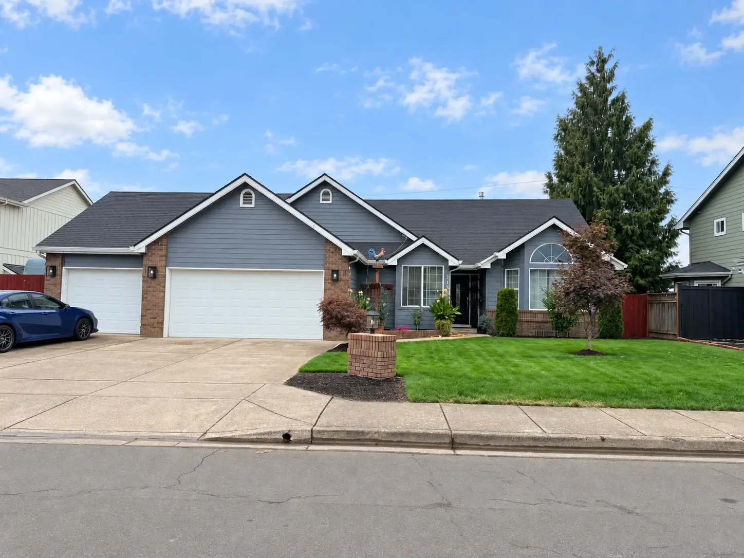 Blue-gray single-level home with brick accents and a three-car garage