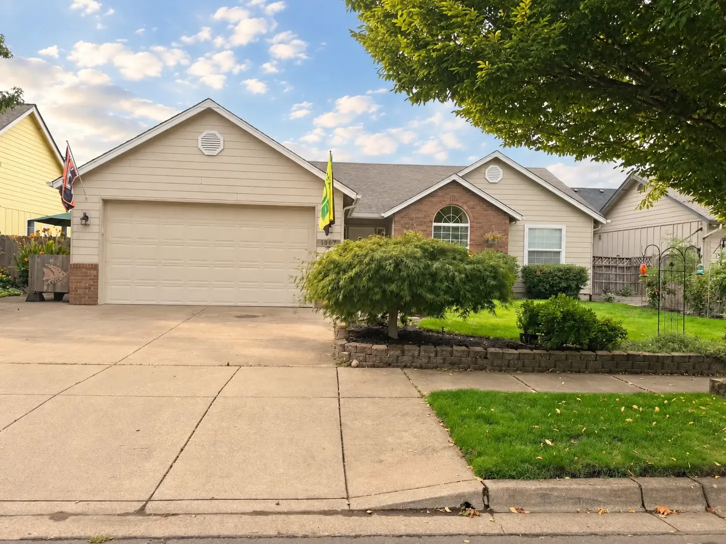 Single-level home with a two-car garage, brick accents, and a maple in the front bed